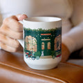 White ceramic mug with colorful bookstore image wrapped around mug.