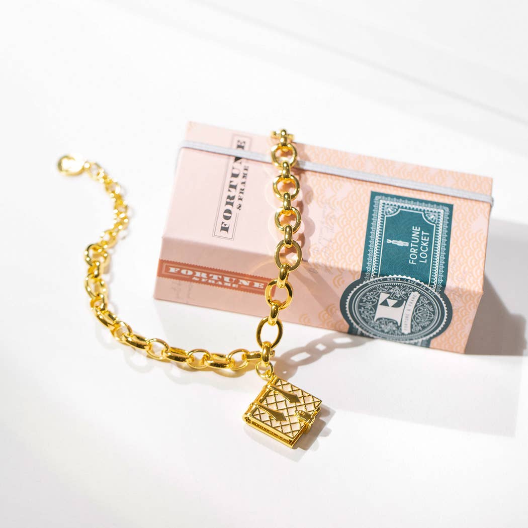 Gold tone chain bracelet with an ivory book charm that opens.