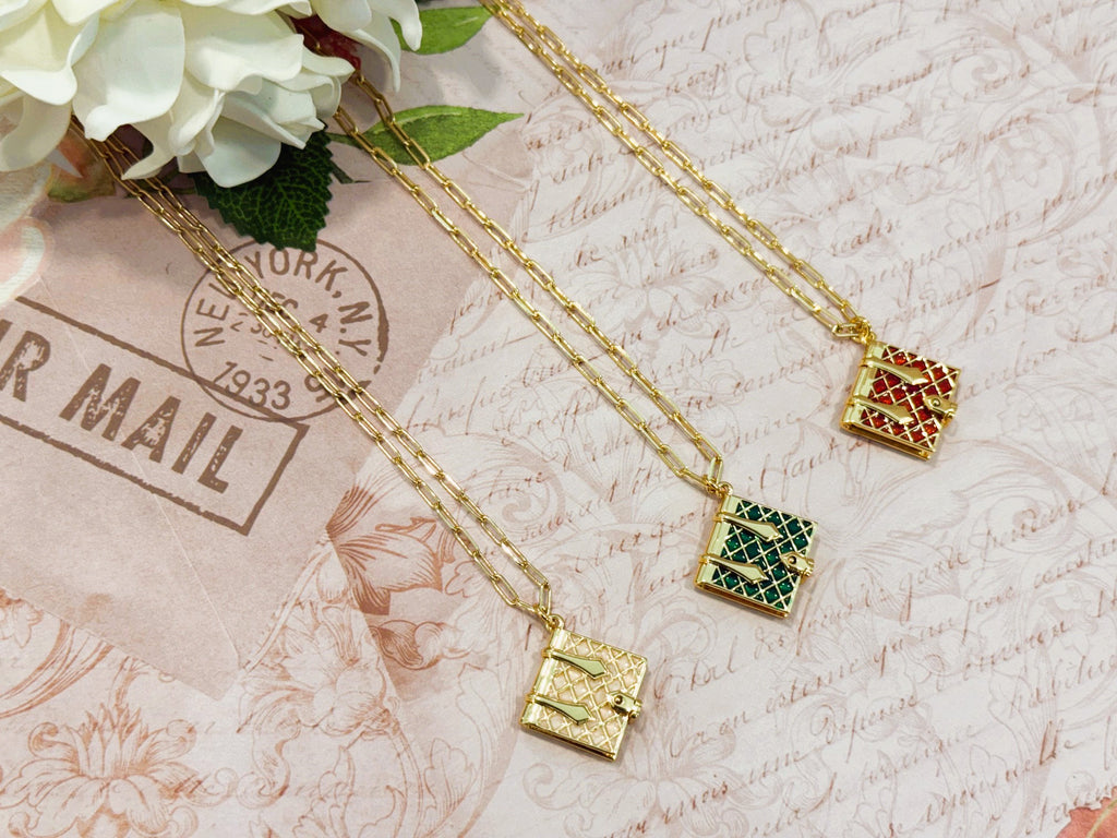 Gold tone necklace with a burgundy, hunter green, or ivory enamel book charm that opens.